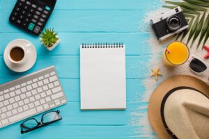 Bureau de courtier en assurance entre travail et vacances, avec clavier, boisson, appareil photo et bloc-notes